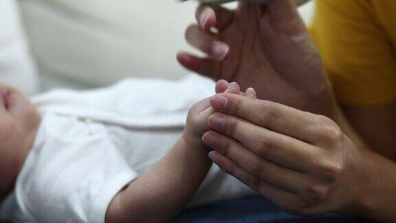 母亲在家里给婴儿剪指甲
