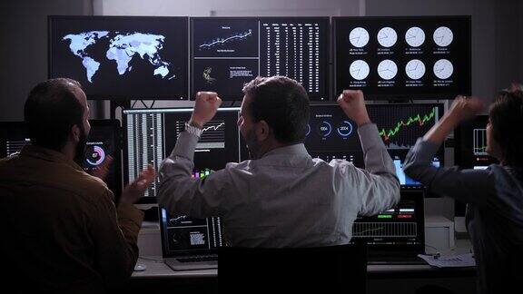 一群交易员股票市场经纪人在多个电脑屏幕上分析图表庆祝