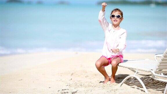 白色的沙滩上快乐的小女孩手里拿着玩具飞机孩子们在海滩上玩玩具