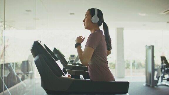 亚洲运动妇女在健身房的跑步机上锻炼