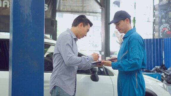 亚洲汽车技师在车库里向客户讲解汽车状况车辆维修经理男在机械车间工作负责车辆零部件的维修工作