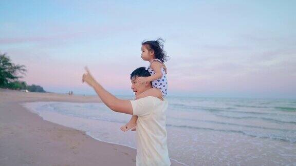 亚洲可爱的女儿坐在父亲的肩膀而散步在海滩上度假的白天时间