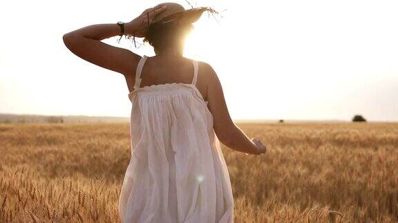 年轻女子拿着她的草帽在麦田里奔跑太阳在晴朗的天空中照耀夏天的一天罕见的视图