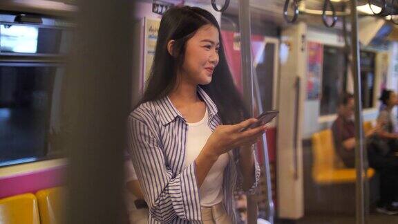 一名年轻的亚洲女子在地铁上使用智能手机