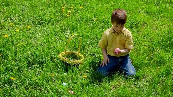 草地上的男孩收集五颜六色的复活节彩蛋