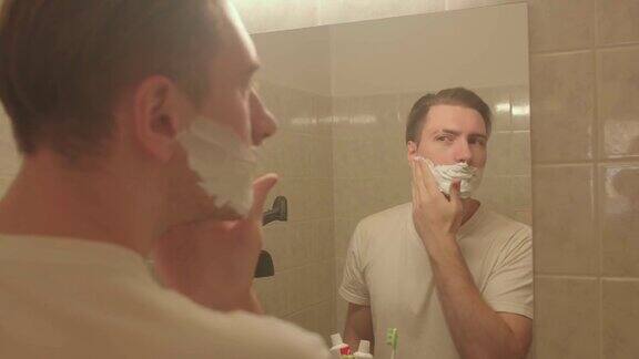 男士将剃须泡沫涂在脸上他在算盘上搓手准备刮脸