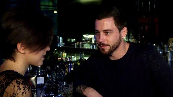 一个英俊的年轻人在酒吧和他漂亮的女朋友聊天