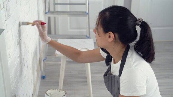 年轻女子在粉刷公寓或房子的墙壁
