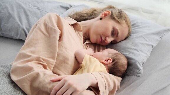 母亲抱着她的婴儿在床上睡觉