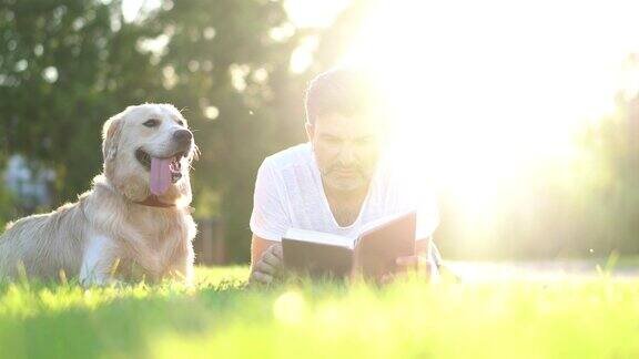 狗主人和他的宠物在公园里读书