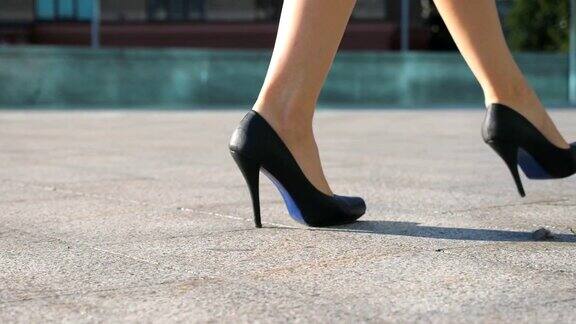女人们穿着高跟鞋走在城市的街道上穿着高跟鞋的年轻女商人的脚在城市中穿行女孩走着去上班慢动作近景低角度视图