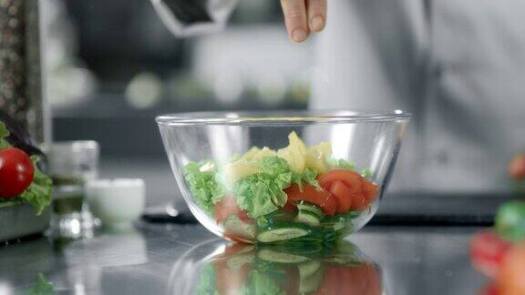厨师在厨房餐厅给沙拉加盐用手腌制蔬菜的特写