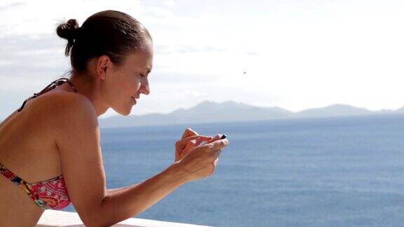 一名年轻女子在蓝色海水中户外使用手机