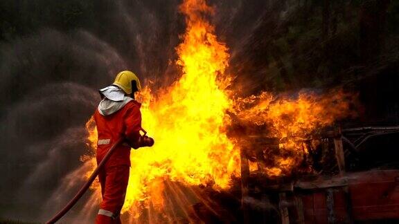 一名勇敢的消防队员用螺旋形水龙带扑灭一场车祸中的大火的慢镜头