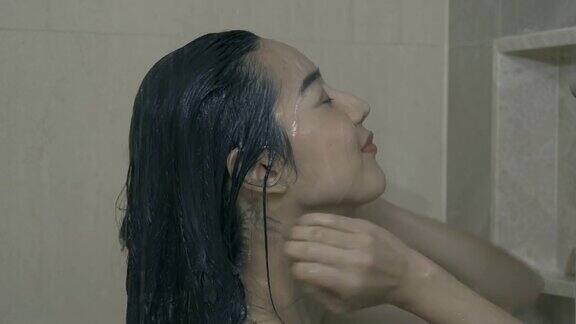 漂亮的女人正在洗热水澡用洗发水洗掉头发