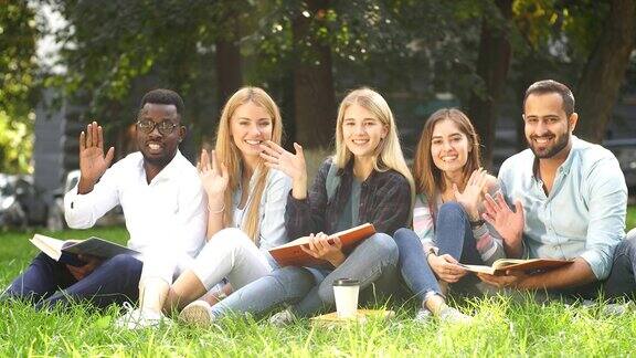 一群不同种族的学生坐在大学校园的绿色草坪上