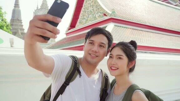 亚洲的博主夫妇在曼谷旅行泰国甜蜜的夫妇使用手机自拍视图而花甜蜜的时间在假日旅行日落情侣旅游城市概念