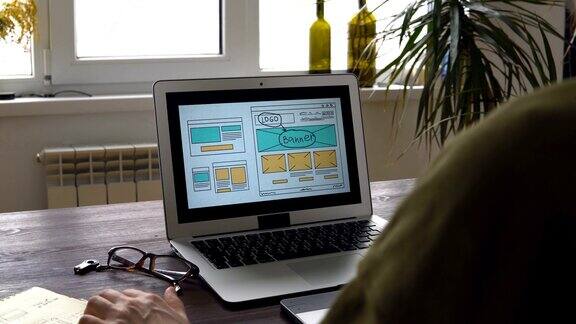 Web开发人员坐在桌子前绘制未来网站的草图在家办公远程办公