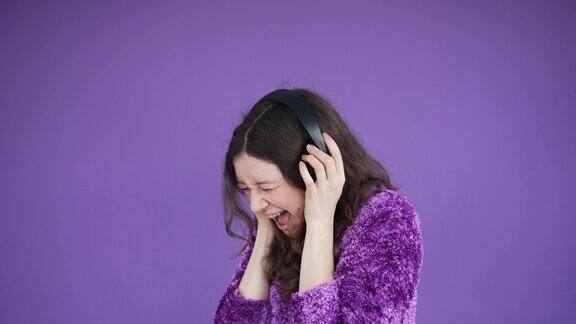 一名年轻女子戴着耳机听着嘈杂的音乐大喊大叫