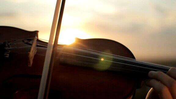 小提琴家在日落时演奏弦乐器小提琴
