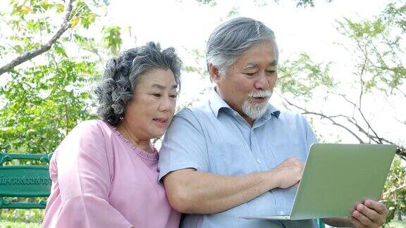 亚洲夫妇老年人一起在公园放松老年人用笔记本电脑心情愉快人们生活方式