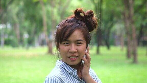 亚洲女孩转身在公园里用智能手机聊天