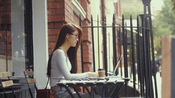 年轻的中国学生在咖啡馆使用笔记本电脑(慢镜头)