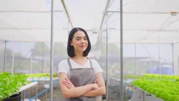 亚洲女农主在蔬菜水培农场工作与幸福年轻女子交叉手臂看着镜头微笑幸福和骄傲在温室农场