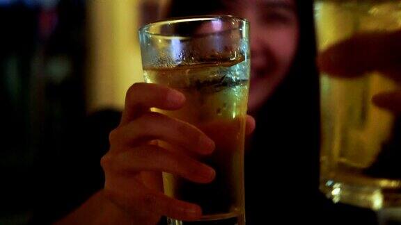 慢动作FHD镜头特写亚洲女人敬酒和碰杯啤酒与朋友在酒吧和餐厅放松和饮料