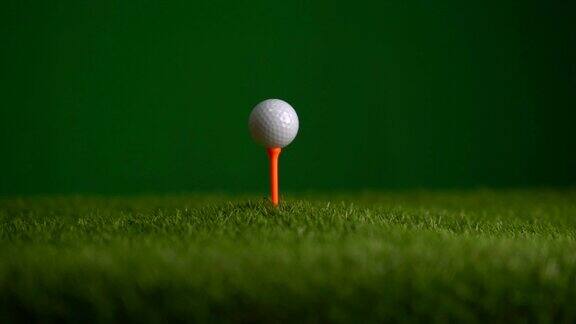 高尔夫球在球座上的慢动作滑动在高尔夫球场上的绿色背景