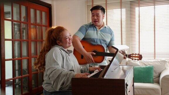 亚洲夫妇音乐家一起弹钢琴吉他