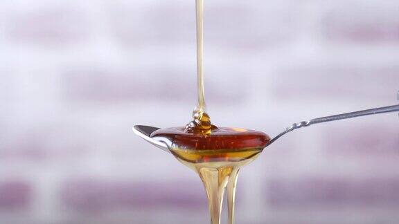 新鲜蜂蜜滴在勺子上的特写