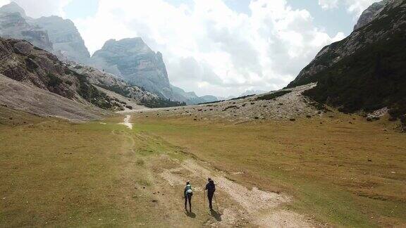 一对夫妇沿着一条穿过意大利白云石山谷的砾石小路徒步旅行四周是高耸的山峰石头和原始的景观偏僻荒凉的地方自由的探索