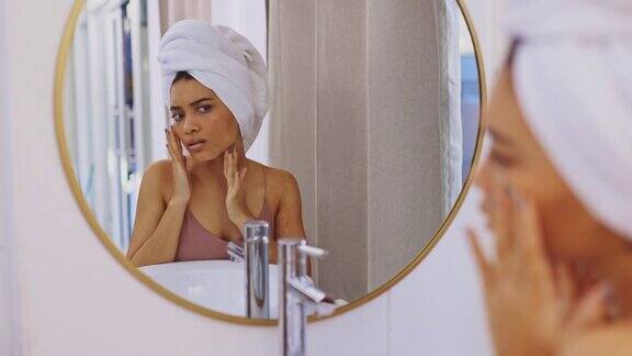 4k视频一个迷人的年轻女人在浴室镜子里审视自己的脸