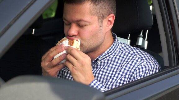 慢镜头中一个年轻英俊的男子正在一辆车里吃汉堡包