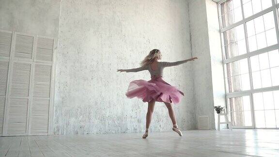 那个芭蕾舞者穿着经典的芭蕾舞短裙和尖头鞋在转圈一个年轻的芭蕾舞演员踮着脚尖在一扇明亮的大窗户的背景上跳舞慢动作