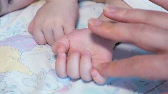 母亲爱抚着熟睡的婴儿的手