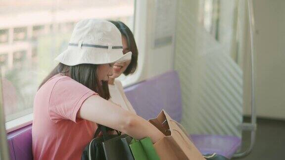 两个年轻的亚洲女人在地铁上展示她们新买的东西慢动作