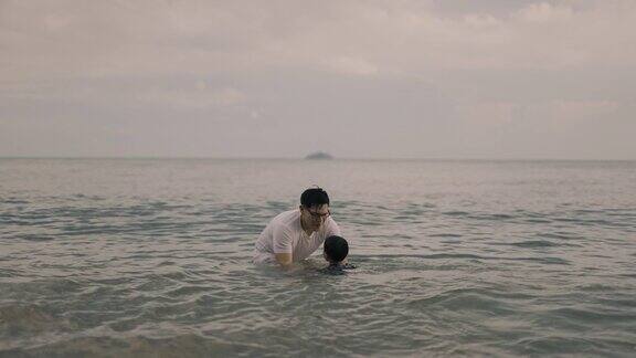在海滩上父亲把儿子从海水中抬起来
