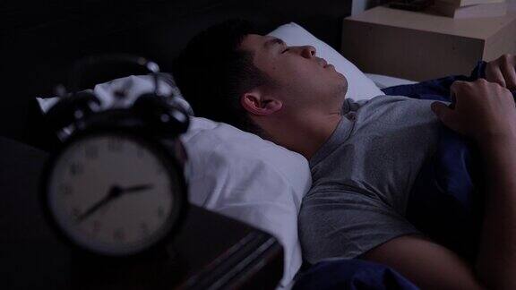 年轻的亚洲男子失眠躺在床上
