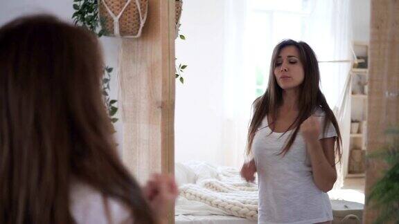 迷人的年轻女子正站在卧室镜子前寻欢作乐