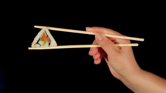 女人的手用筷子夹着寿司就黑了