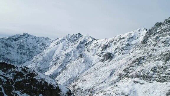 向前鸟瞰图在冬季雪山岩石山峰落基山脉的峰顶被冰雪覆盖冬季野外自然景观户外建立全高清无人机飞行建立镜头