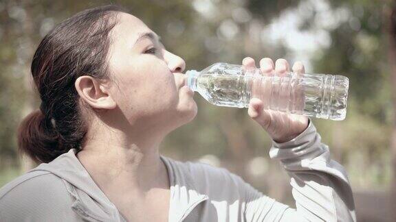 在公园里喝水的女人