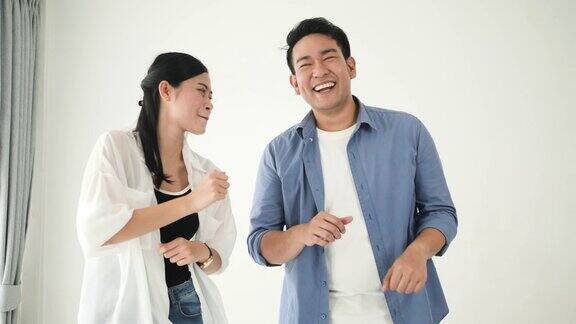 快乐的亚洲情侣在家里一起跳舞慢镜头