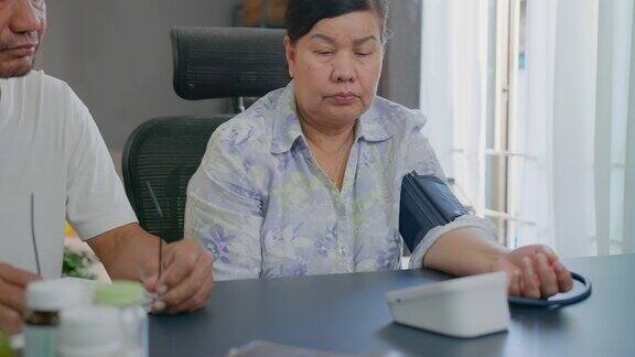特写亚洲资深妇女在家检查血压和心率