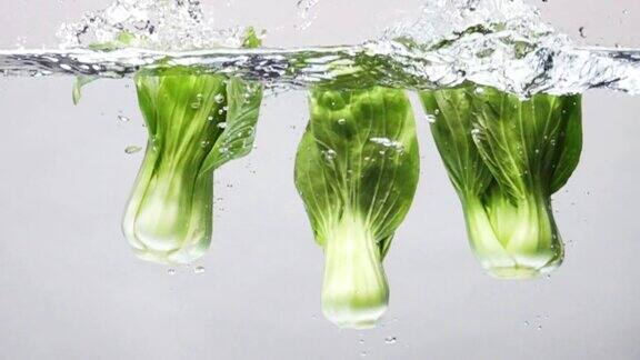 超级慢动作:白菜在白色背景下掉进淡水中