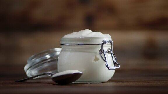 酸奶油在桌子上的一个玻璃罐子里慢慢旋转