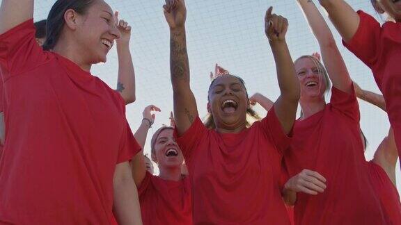 兴奋的女子足球队庆祝胜利的肖像从低角度射门