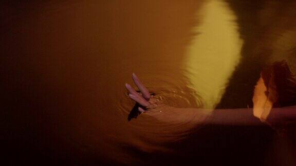 金色的光滑的水面女性用手轻轻泼洒并触摸液体